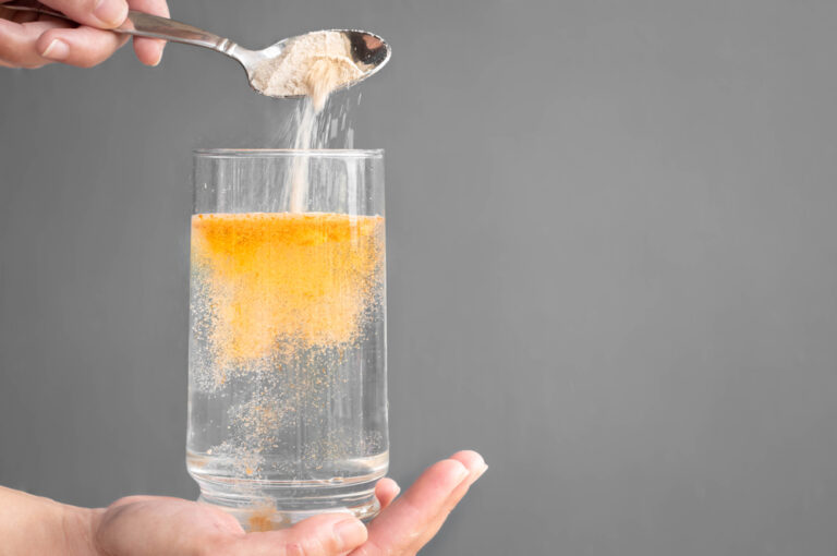 An orange fizzy powder poured in a glass of water.