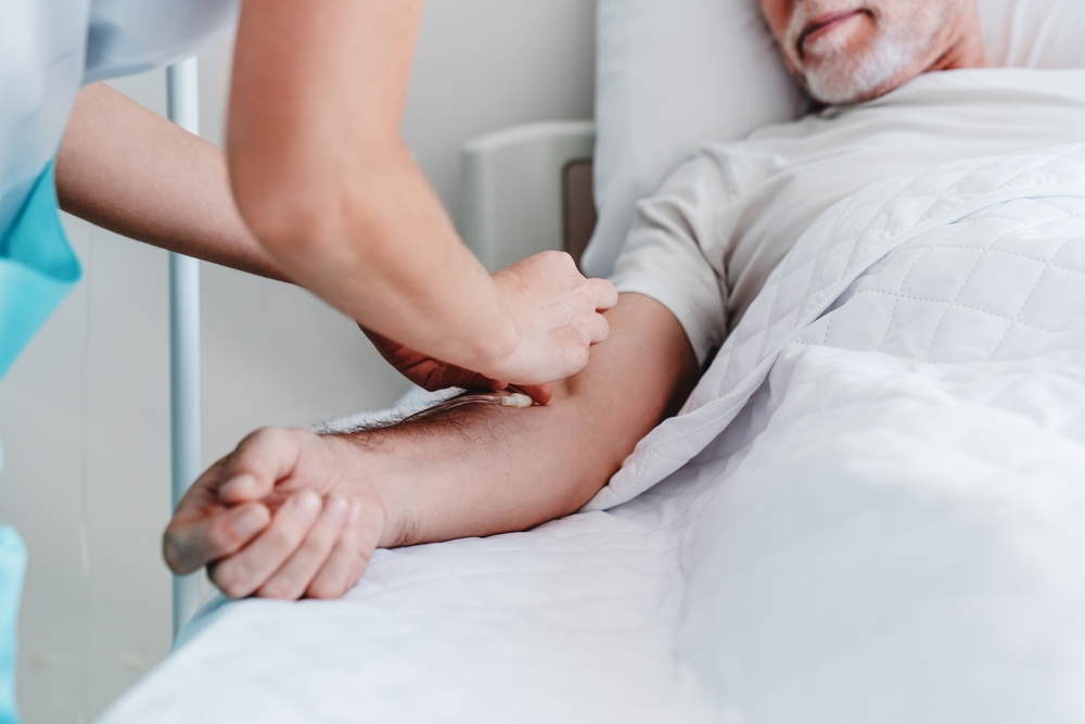 Caucasian Nurse putting a dropper to ill male patient in the hospital