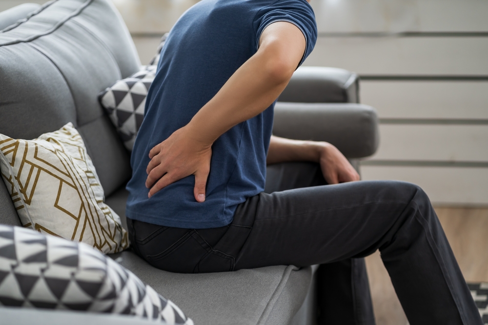 A man on a couch suffering backache due to kidney inflammation.