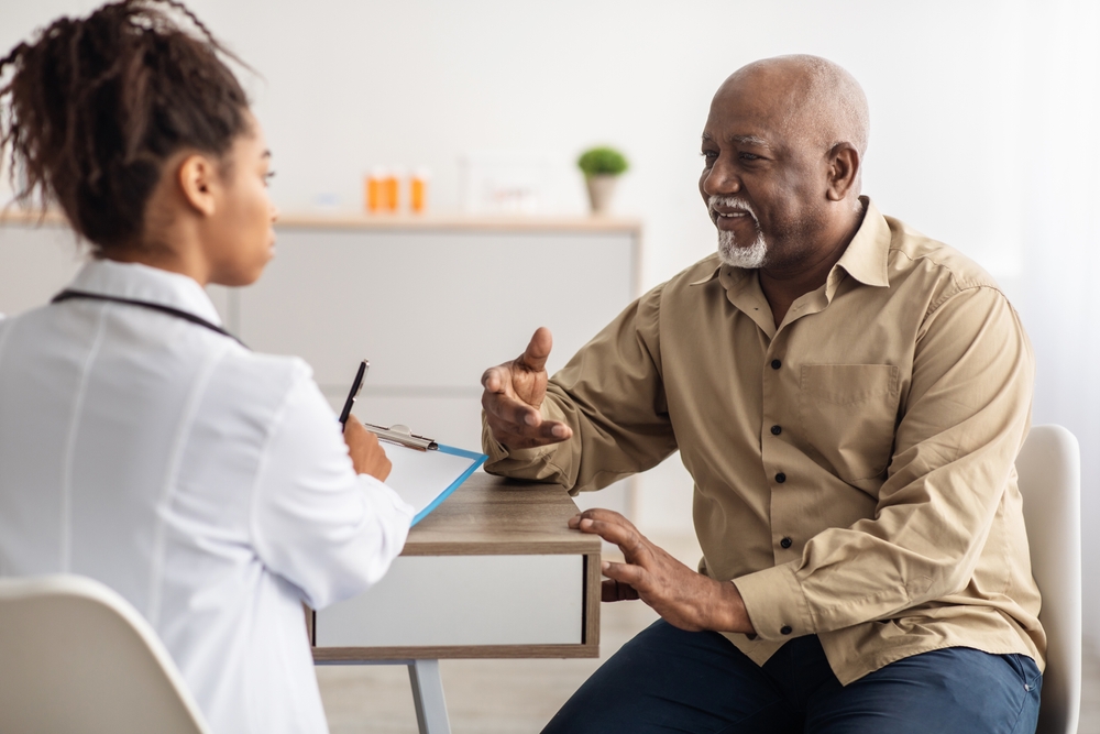 A woman kidney doctor conducting a medical checkup to a senior man about his kidneys.